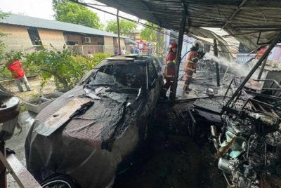 Anggota bomba sedang memadamkan kebakaran di bengkel berkenaan.