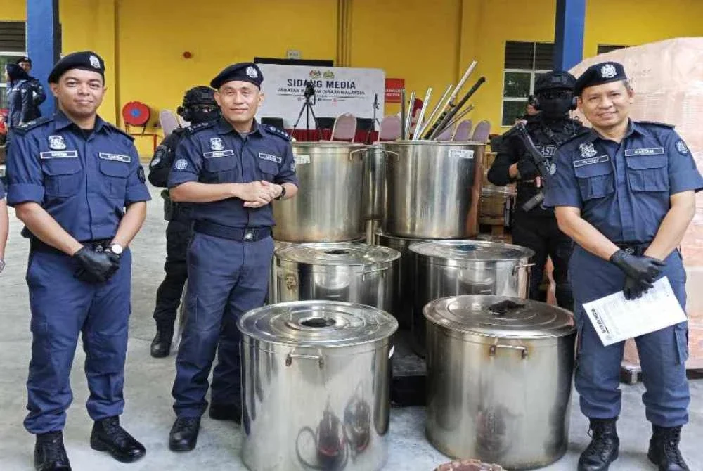 Aminul Izmeer (tengah) menunjukkan periuk yang digunakan sindiket untuk memproses air ketum di Kempas.