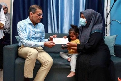 Ketua Pegawai Eksekutif Kumpulan PERKESO Datuk Seri Dr Mohammad Azman Aziz Mohammed menyerahkan Pencen Penakat dan Faedah Pengurusan Mayat (FPM) PERKESO kepada Nor Nadia Abdul Majid (kanan), balu kepada Allahyarham Amirul Hafiz Omar, 33, ketika menziarahi keluarga tersebut di kediamannya hari ini.Foto Bernama 