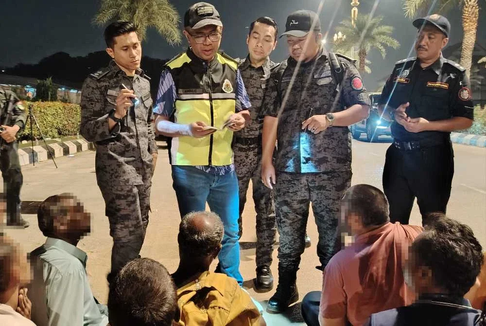 Khairrul Aminus (dua dari kiri) melakukan pemeriksaan dokumen warga asing yang ditahan dalam serbuan di penempatan haram di Setia Alam, Shah Alam pada Jumaat.