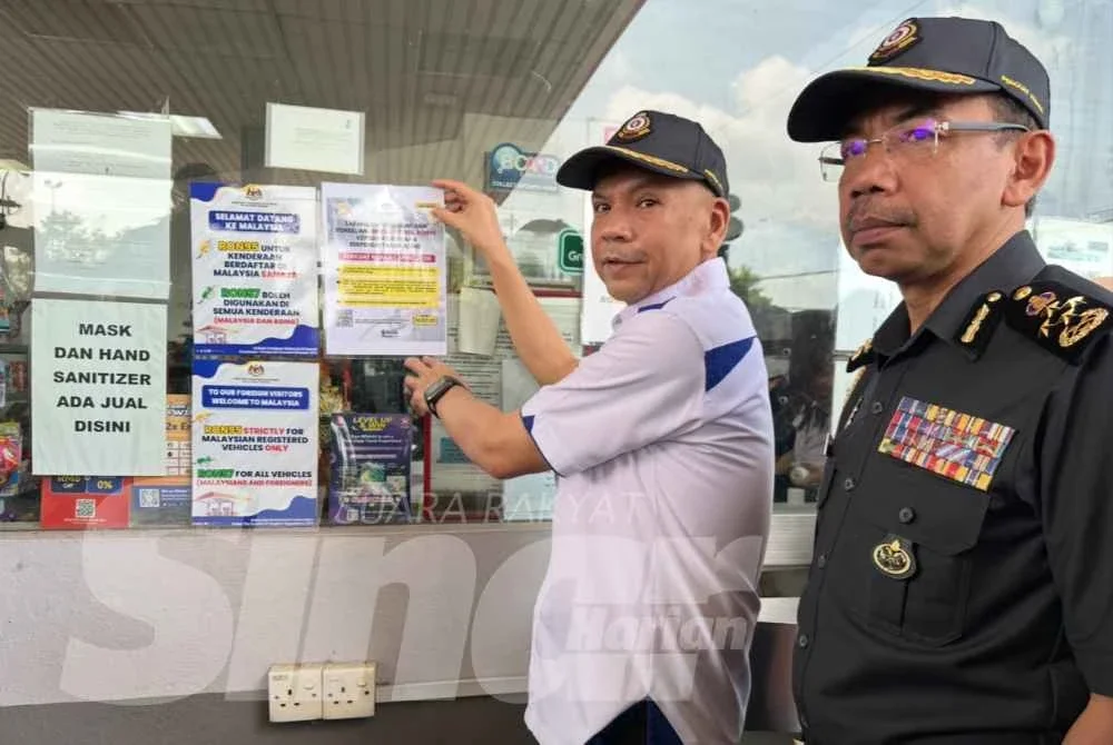 Armizan (dua dari kanan) menampal risalah Larangan Penjualan dan Pembelian Minyak RON95 kepada Kenderaan Berpendaftaran Asing. - Foto:SINAR HARIAN/ADILA SHARINNI WAHID