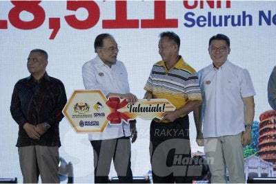 Anwar (dua dari kiri) menyempurnakan sumbangan Sentuhan Kasih KPKT sempena Program Madani Rakyat di Bulatan Sultan Azlan Shah, Meru Raya pada Sabtu.