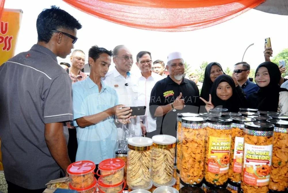 Anwar (tiga dari kiri) melawat reruai pameran Program Perdana Menteri Bersama Warga Peneroka Felda.