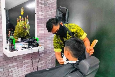 Azuan Hafiezi menggunakan kemahirannya memberikan perkhidmatan gunting rambut percuma sempena Program Madani Rakyat 2026 di Bulatan Sultan Azlan Shah, Meru Raya pada Sabtu.