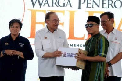 Anwar (dua dari kiri) menyampaikan bantuan kepada penerima pada program bersama warga Felda di Felda Semenchu, Kota Tinggi.