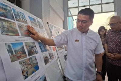 Kor Ming ketika meninjau paparan kejayaan pelaksanaan projek naik taraf Medan Selera Greentown Utama, Ipoh pada Ahad.
