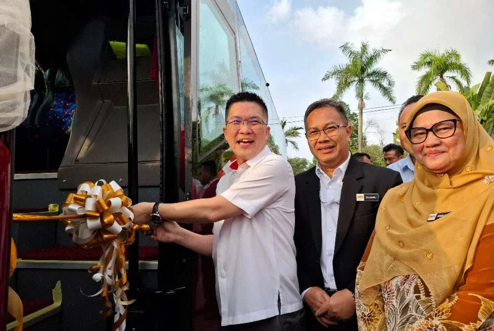 Kah Woh (kiri) menyempurnakan gimik perasmian Penyerahan Bas kepada Sekolah Menengah Kebangsaan (SMK) Raja Permaisuri Bainun di Ipoh pada Isnin.