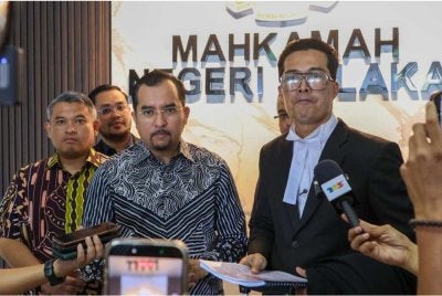 Asyraf Wajdi bersama peguamnya, Adnan (kanan) ketika ditemui di pekarangan Mahkamah Negeri Melaka pada Isnin.