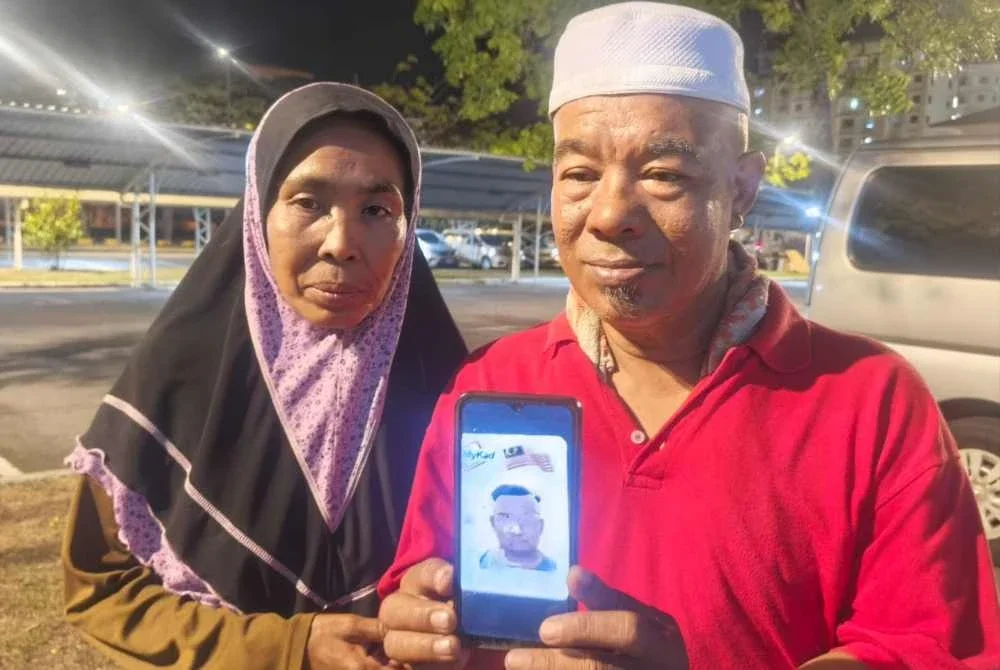 Ahmad Tarmizi (kanan) menunjukkan gambar arwah anaknya Muhammad Zulkifli