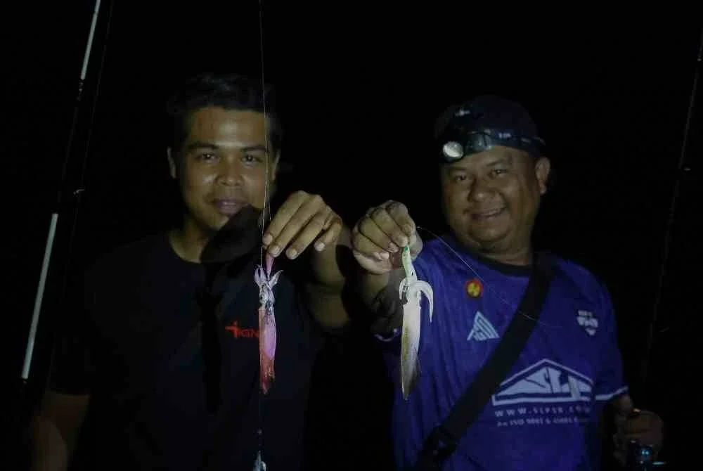 Mohd Norham Yahaya, 41, (kanan) bersama rakan Ahmad Syawal Kamarudin, 30, menunjukkan sotong jarum yang dicandatnya semasa ditemui di Jeti Star Cruise Kijal di Pantai Awana malam tadi. Foto Bernama