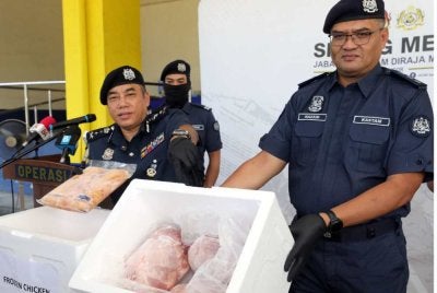 Mohamad Azhar (kiri) menunjukkan daging ayam sejuk beku pada sidang akhbar di Pejabat Kastam Pelabuhan Utara, Klang pada Selasa.