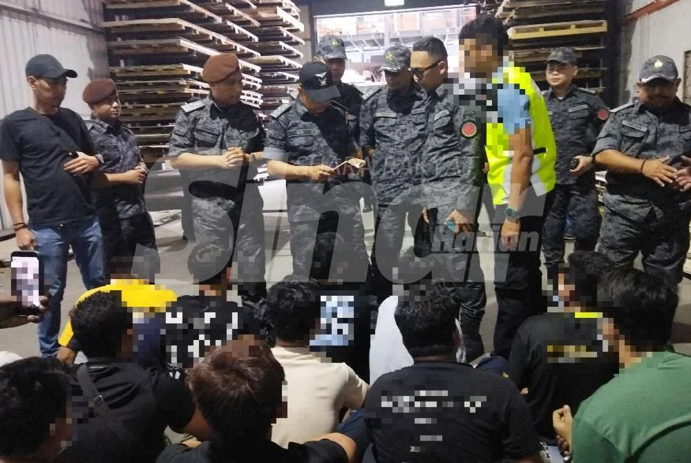 Zakaria (empat dari kiri) memeriksa dokumen pekerja sebuah kilang yang diserbu pada Rabu.