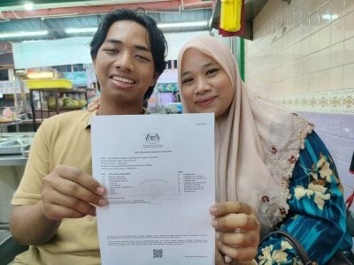 Muhammad Fiqkrie bersama Zaiton menunjukkan slip keputusan SPM yang diperoleh baru-baru ini.