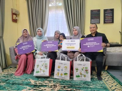 Norliza (dua dari kiri) menyerahkan sumbangan kepada Nor Nadia (tengah) ketika Program Ziarah Kasih PTPTN di Kampung Repoh di sini pada Selasa.