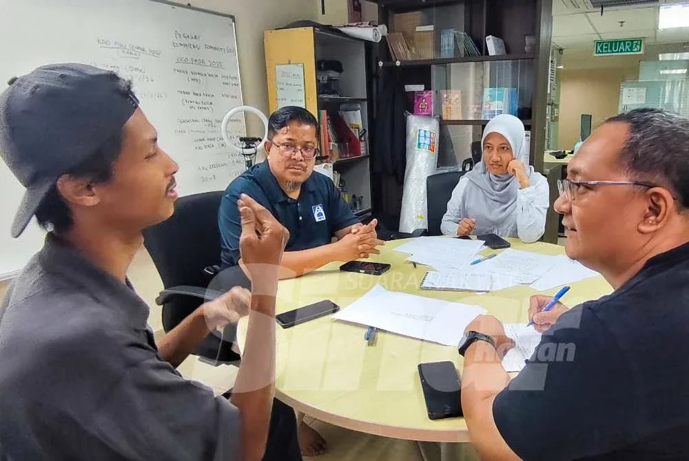 Mohammad Taqiyyuddin sedang memberitahu sesuatu menggunakan bahasa isyarat kepada Muhamad Firdaus ketika ditemui Sinar Harian. Foto Sinar Harian