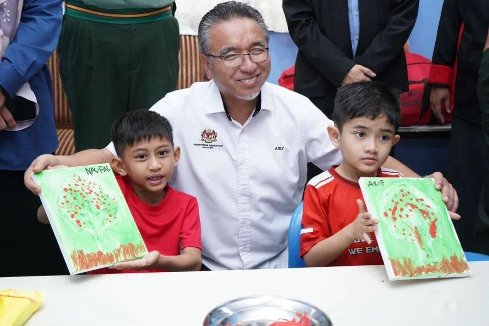 Adly (tengah) beramah mesra dengan dua kanak-kanak autisme yang menjalani terapi di IA-Autisme Kem Terendak pada Rabu.