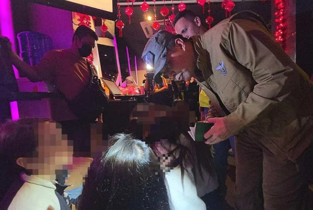 Lokman memeriksa dokumen wanita warga asing yang ditahan dalam serbuan Op Gegar di sebuah pusat hiburan di ibu negara.