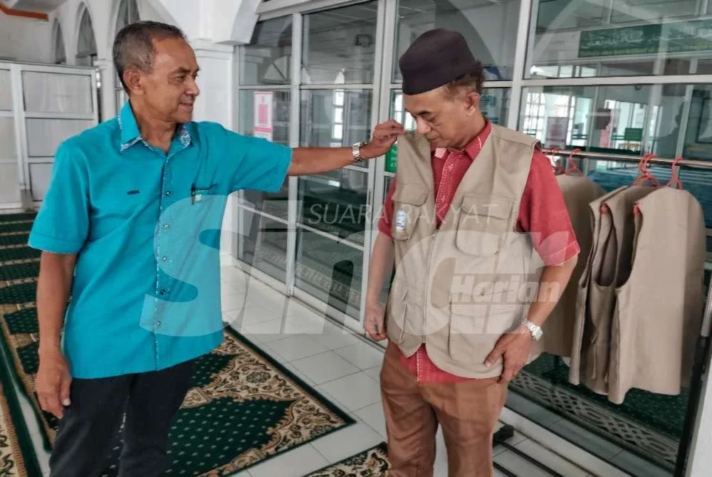 Idros membantu seorang jemaah yang mencuba jaket solat ketika ditemui Sinar Harian pada Khamis.