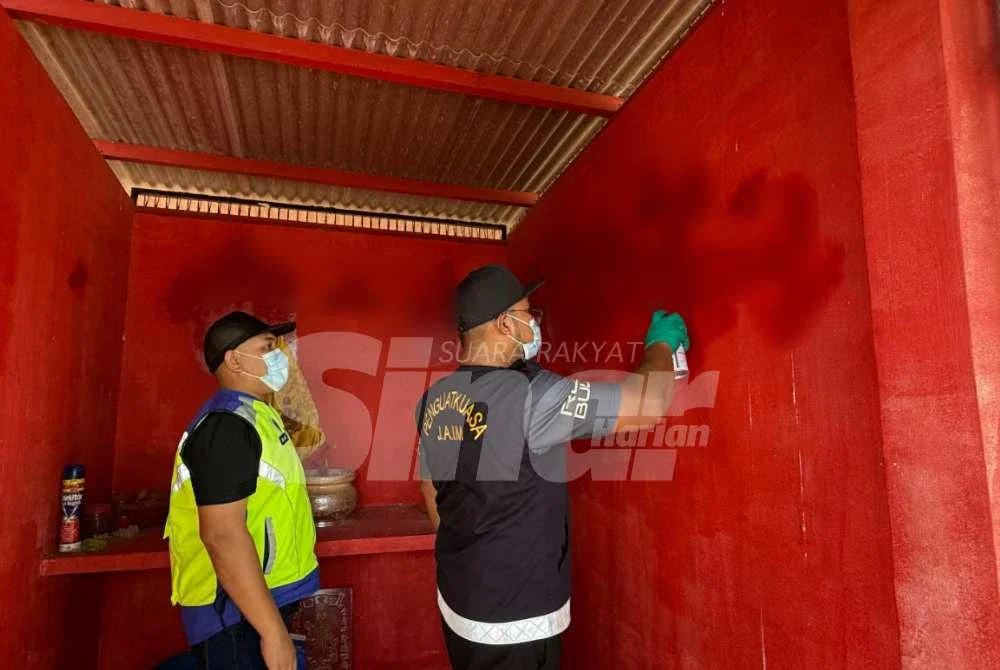 Penguat kuasa JAIM memadam kalimah ALLAH menggunakan cat pada dinding tokong berkenaan. Foto Sinar Harian 