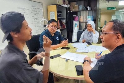 Mohammad Taqiyyuddin sedang memberitahu sesuatu menggunakan bahasa isyarat kepada Muhamad Firdaus ketika ditemui Sinar Harian. Foto Sinar Harian