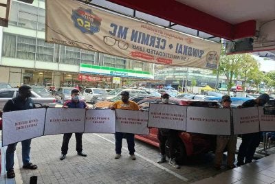 Beberapa orang awam memegang poster di depan pejabat Invoke Solution di sini, hari ini.