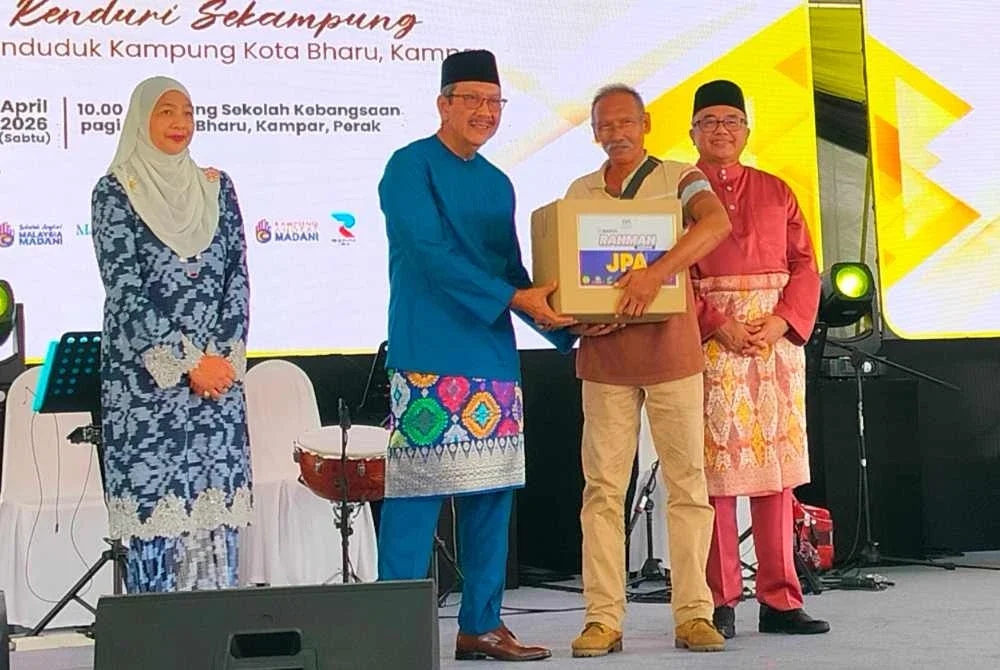Wan Ahmad Dahlan (dua dari kiri) menyerahkan sumbangan kepada penerima sempena Majlis Pelancaran Program Kampung dan Sekolah Angkat Madani JPA di Padang Sekolah Kebangsaan Kota Bharu pada Sabtu.