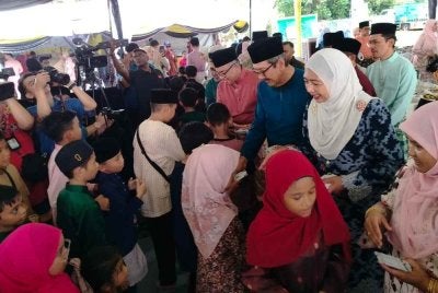 Wan Ahmad Dahlan (tiga dari kanan) turut menyampaikan duit raya kepada kanak-kanak yang hadir sempena Majlis Pelancaran Program Kampung dan Sekolah Angkat Madani JPA di Padang Sekolah Kebangsaan Kota Bharu pada Sabtu.