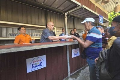 Armizan menyantuni masyarakat setempat semasa mengedarkan makanan pada program 'Dapur Kita-Kita' di Kota Kinabalu.