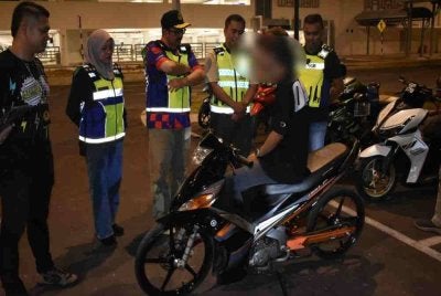 Penunggang dan motosikalnya diperiksa sebelum dikenakan saman atas pelbagai kesalahan. Foto: JPJ