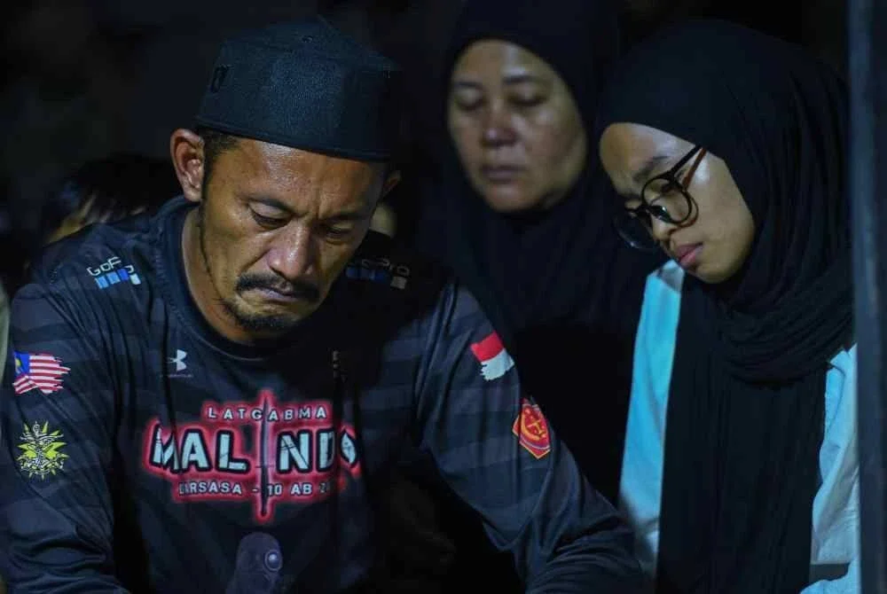 Rosafindi Tambi Chik (kiri) bapa kepada Allahyarham Muhammad Amirul Raziq kelihatan sugul sejurus selesai pengebumian anaknya di Tanah Perkuburan Felda Sungai Kelamah, Gemas, malam tadi. Foto Bernama