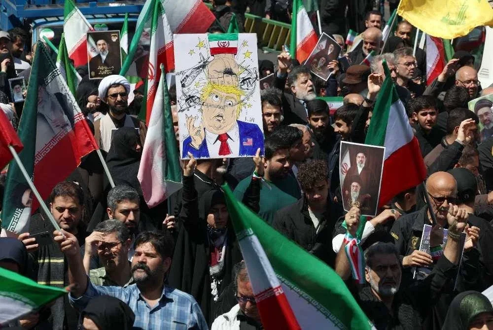 Seorang wanita memegang poster menyindir Presiden Amerika Syarikat, Donald Trump dalam satu perhimpunan di Teheran. -AFP