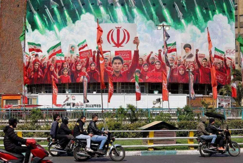 Penunggang motosikal melalui kawasan papan iklan besar di Dataran Valiasr, Teheran yang menunjukkan solidariti rakyat terhadap kerajaan.-AFP