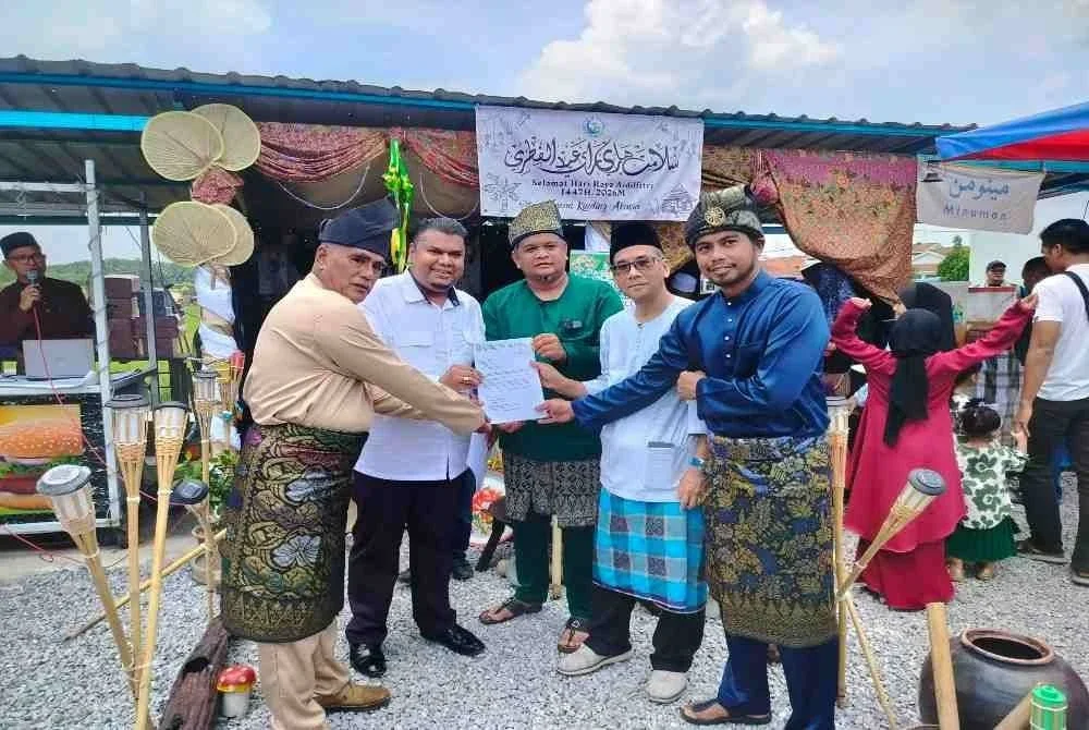 Muhamad Arafat (dua dari kiri) menyerahkan salinan surat maklum balas daripada pihak berkaitan kepada empat pengerusi persatuan penduduk taman perumahan terlibat bagi penyelesaian jangka panjang isu banjir kilat di kawasan berkenaan ketika hadir ke majlis Rumah Terbuka Aidilfitri Taman Kinding di sini pada Ahad.