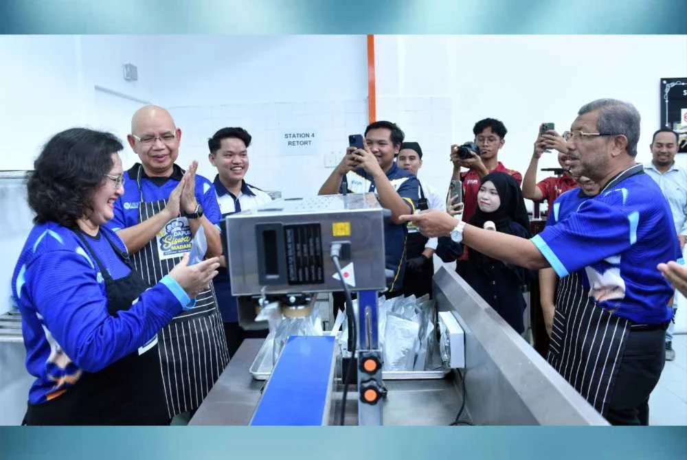 Dr Azlinda diberikan penjelasan mengenai fungsi mesin “continuous band sealer” bagi meningkatkan kebersihan dan jangka hayat produk Dapur Siswa MADANI@UUM sambil disaksikan Dr Mazlan dan Dr Ahmad Martadha.