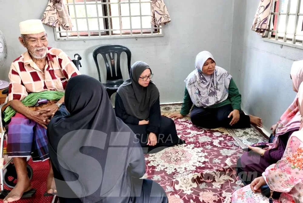 Zuraifah (kanan) melayan sanak saudara yang datang ke rumah di Kampung Gayong, Kota Bharu pada Isnin.