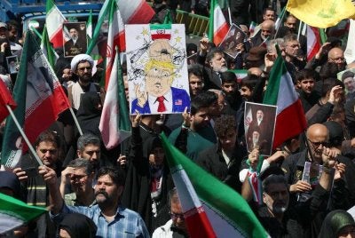 Seorang wanita memegang poster menyindir Presiden Amerika Syarikat, Donald Trump dalam satu perhimpunan di Teheran. -AFP 