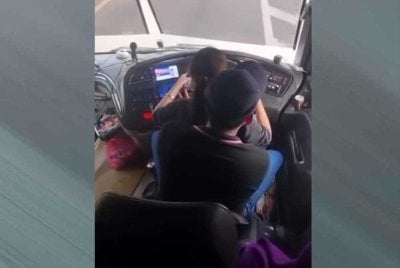 Tangkap layar rakaman video tular pemandu bas ekspres memangku wanita ketika kenderaan sedang bergerak.