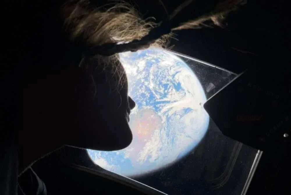 Pakar misi Artemis II, Christina Koch melihat kembali ke arah Bumi melalui tingkap kapsul Orion. Foto AFP