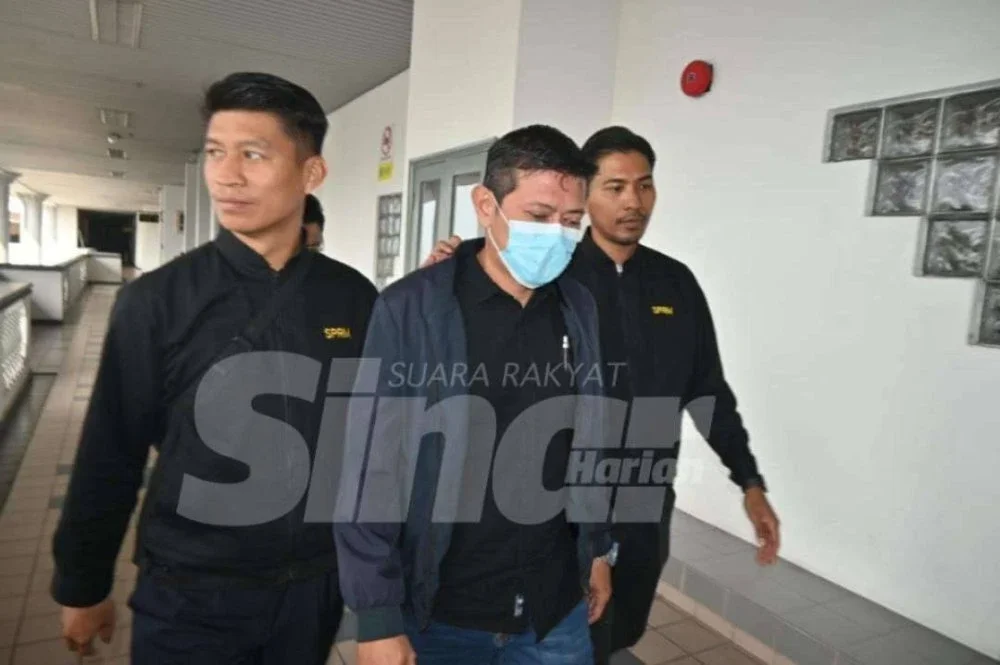 Tertuduh (tengah) mengaku tidak bersalah terhadap dua pertuduhan ke atasnya.