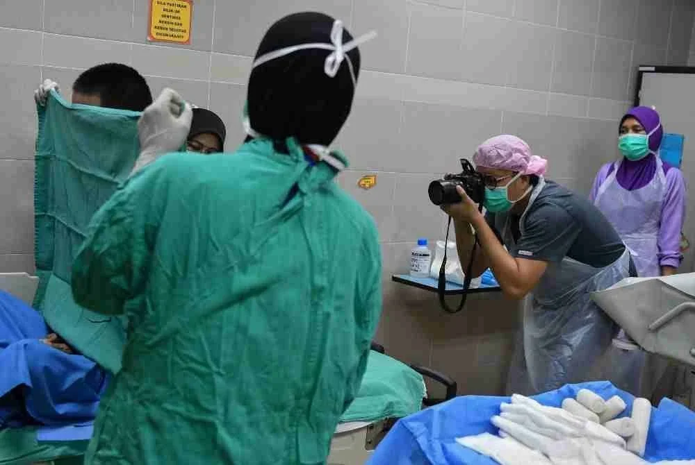 Kakitangan Unit Rawatan Kebakaran (URK) Hospital Pakar Universiti Sains Malaysia (HPUSM) mengambil gambar luka melecur pada badan Ahmad Nasri Anwar, 31, di HPUSM, Kubang Kerian baru-baru ini. Foto Bernama