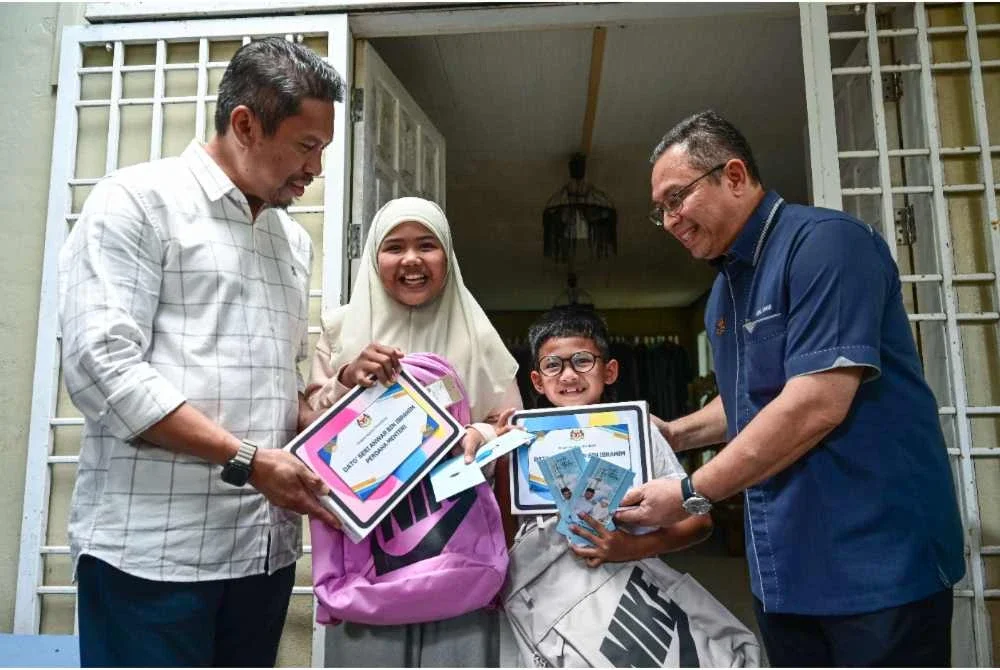 Abdul Kahar (kanan) menyampaikan sumbangan dan duit raya kepada Aesha Khadeeja (dua, kiri) dan adiknya, Uwais AlQorni (dua, kanan) ketika ditemui di kediaman mereka di Ladang Titian pada Selasa. Foto Bernama