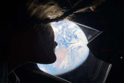Pakar misi Artemis II, Christina Koch melihat kembali ke arah Bumi melalui tingkap kapsul Orion. Foto AFP