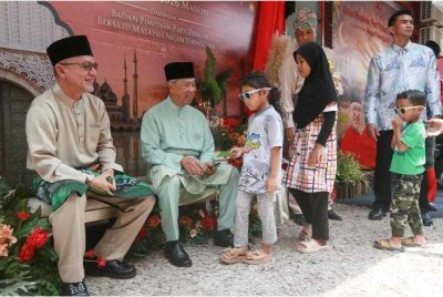 Muhyiddin (dua dari kiri) menyampaikan duit raya kepada kanak-kanak yang hadir pada Majlis Jamuan Hari Raya Aidilfitri Bersatu Terengganu di Kuala Terengganu pada Rabu.