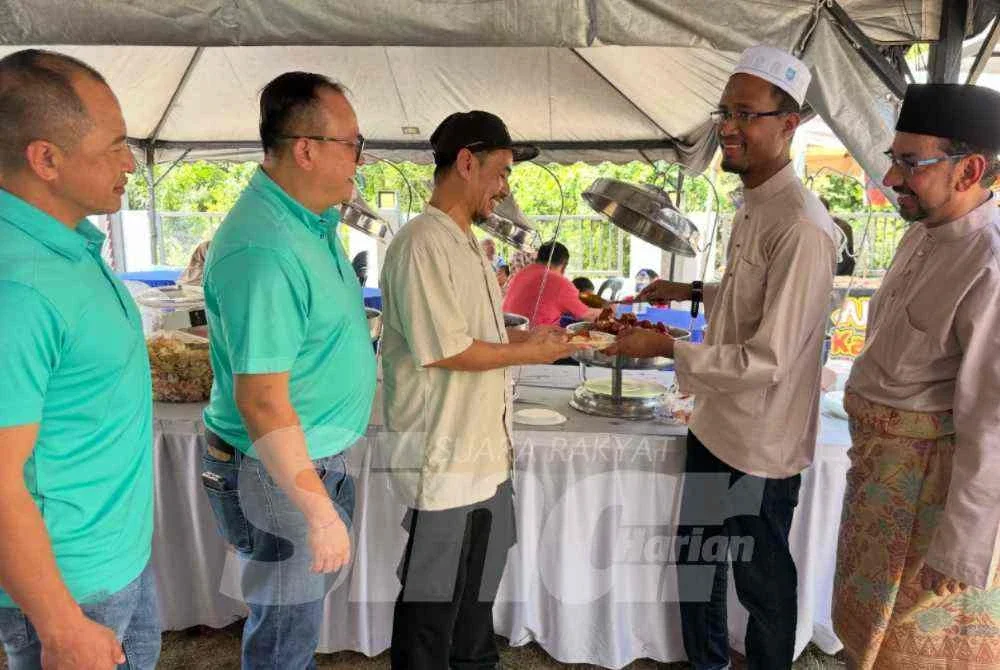 Dr Muhamad Asyraf (dua dari kanan) bersama Salim (kanan) melayani tetamu yang hadir di Rumah Terbuka Raya.
