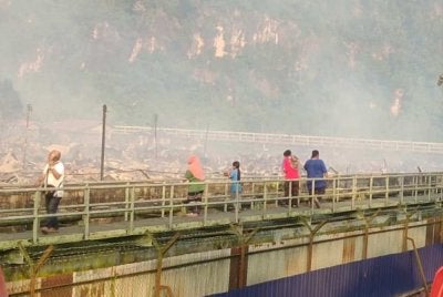 Kelihatan beberapa mangsa melihat keadaan rumah mereka yang musnah dalam kebakaran di Kampung Bahagia, Batu Sapi awal pagi Ahad. 