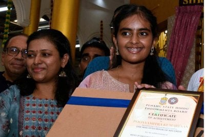 Poonyamitra (kanan) yang mencipta nama dalam Malaysia Book of Records baru-baru ini apabila berjaya menghafal dan menyebut semula 300 digit pertama nombor Pi. Foto: Bernama
