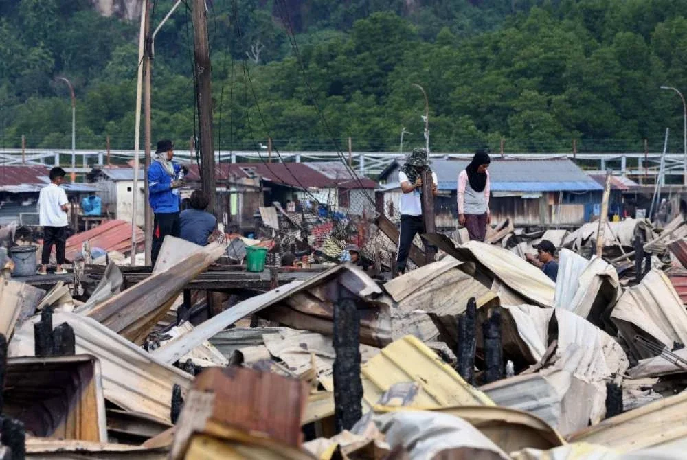 Beberapa penduduk mencari sisa-sisa barangan yang masih boleh digunakan selepas kediaman mereka musnah dalam kebakaran besar di Kampung Bahagia awal pagi Ahad. Foto Bernama