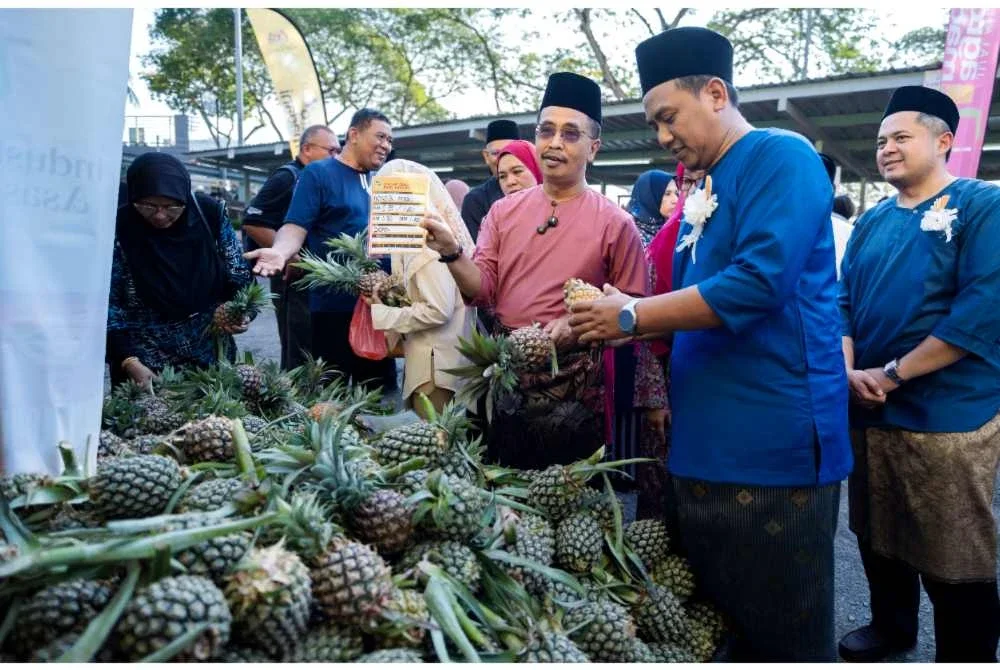 Abdul Rashid (depan, tiga kanan) menunjukkan tanda harga buah nanas madu yang dijual pada harga RM0.50 sebiji pada Program Jualan Agro Madani Edisi Johor di Ibu Pejabat FAMA Bandar Baru Selayang pada Isnin. Foto Bernama