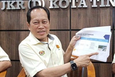 Ahmad menunjukkan laporan kemajuan projek pembinaan Jambatan Kota Tinggi Bypass ketika mengadakan lawatan ke Pejabat JKR Kota Tinggi.
