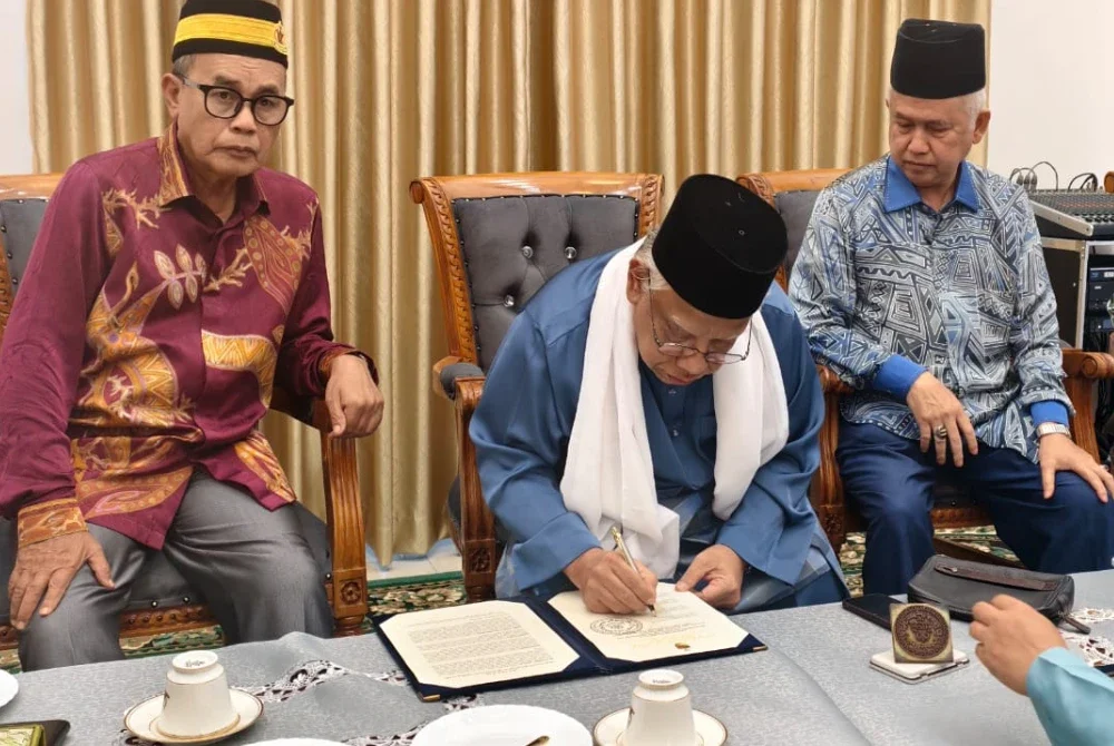 Mubarak (tengah) menandatangani pengisytiharan pemecatan Tuanku Muhriz dalam sidang media khas di Balai Undang Sungei Ujong pada Ahad lalu.